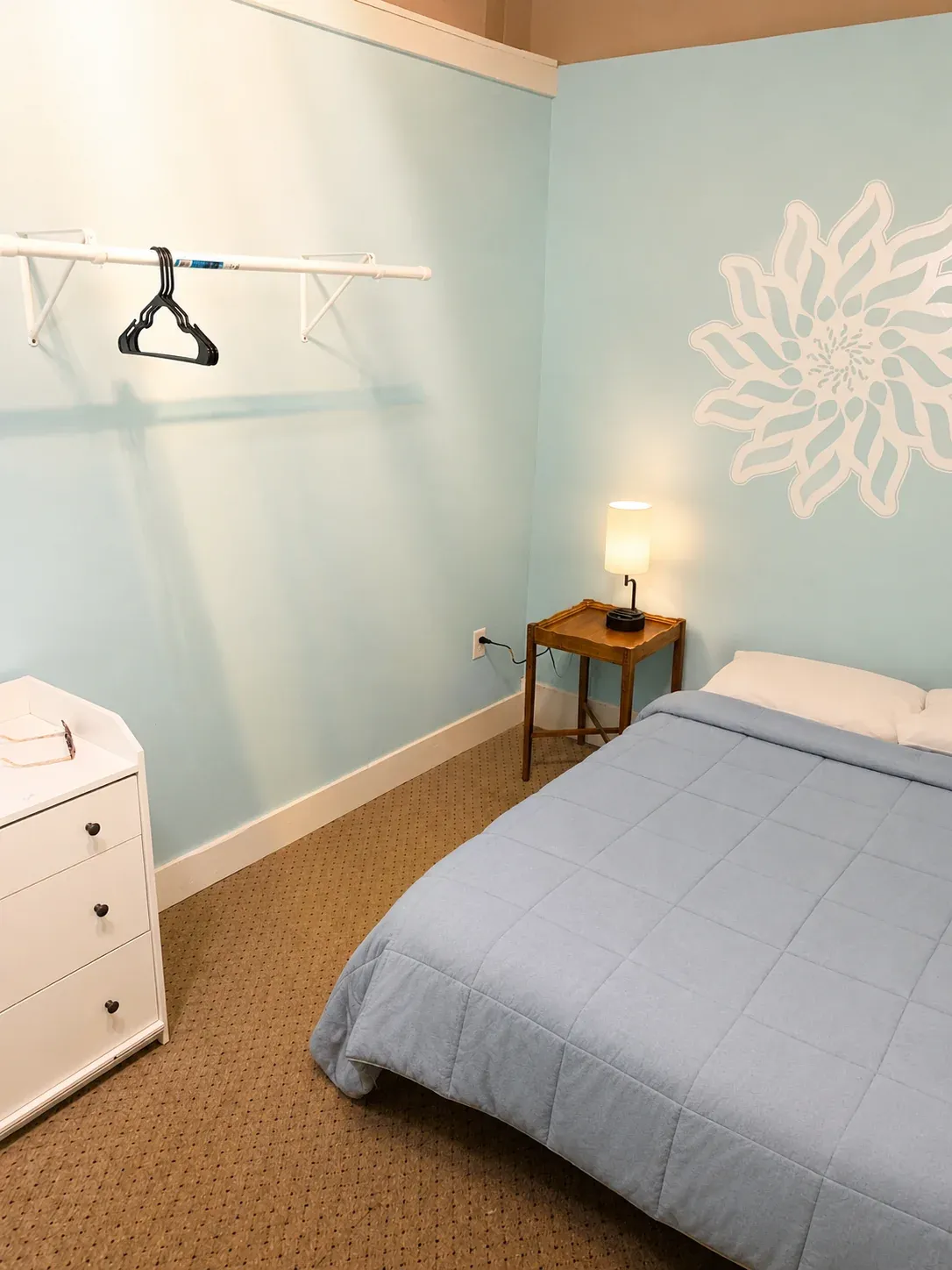 Light blue Annex room with a full bed and painted flower mural